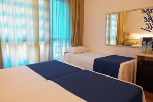 a hotel room with two beds and a mirror at Lloret Vibe Affiliated by FERGUS in Lloret de Mar