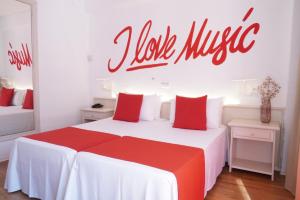 a bedroom with a red and white bed with a sign on the wall at Lloret Vibe Affiliated by FERGUS in Lloret de Mar