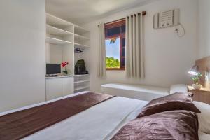 Habitación blanca con cama y ventana en America Praia Flat - Portal Hotéis en Porto Seguro