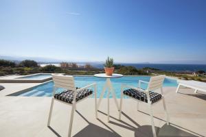 uma mesa e duas cadeiras sentadas ao lado de uma piscina em Pachnes Luxury Apartments - Heated Pool, Sea View em Kounoupidhianá