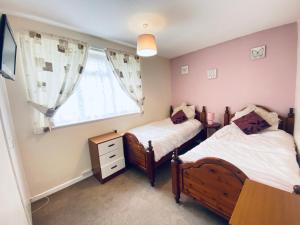 two twin beds in a room with a window at Cosy and Comfortable Holiday Chalet 10 minutes walk to the beach, Norfolk in Great Yarmouth