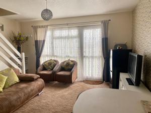 a living room with a couch and a television at Cosy and Comfortable Holiday Chalet 10 minutes walk to the beach, Norfolk in Great Yarmouth