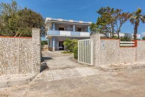 ein Haus mit einem Steinzaun davor in der Unterkunft Villa Spiaggia degli Angeli in Porto Cesareo