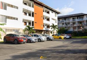 Une rangée de voitures garées dans un parking en face d'un bâtiment dans l'établissement La Géométrie à 5 minutes du centre-ville et de la plage, à Cayenne