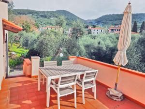 einen Balkon mit einem Tisch, Stühlen und einem Sonnenschirm in der Unterkunft Tra gli Ulivi e il Mare in Tellaro