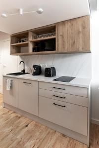 a kitchen with white counters and wooden cabinets at Długa 18 Apartament Premium z antresolą in Poznań
