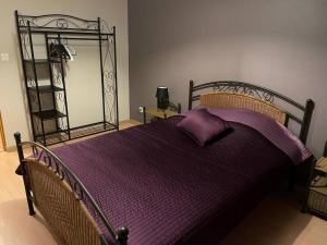 een slaapkamer met een bed met paarse lakens en een spiegel bij La Bergerie in Thilay