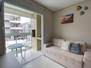 a living room with a couch and a table at Apartamento encantador com piscina na Praia de Palmas Governador Celso Ramos in Governador Celso Ramos