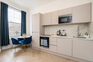 a kitchen with white cabinets and a table and chairs at Modern Apartments Near Harrods and the Science Museum in London