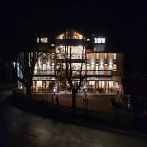 un grand bâtiment avec des lumières devant lui la nuit dans l'établissement Gasthof & Hotel Bichler, à Emmering