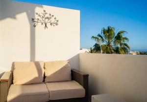 een bank op een balkon met een palmboom bij Dias Felices in Playa Blanca