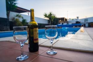 een fles wijn en twee wijnglazen op een tafel bij Dias Felices in Playa Blanca