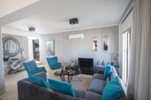 sala de estar con sofá y sillas azules en Tonia Seaview Villas, en Protaras