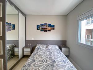 a bedroom with a bed and a large window at Apartamento encantador com piscina na Praia de Palmas Governador Celso Ramos in Governador Celso Ramos +17 photos