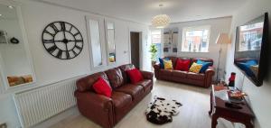 a living room with a couch and a clock on the wall at Riverdale House(4 Bedrooms) Serviced Accommodation in Grimsby