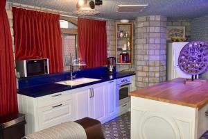 una cocina con armarios blancos y cortinas rojas en The Royal Suite, en Safed