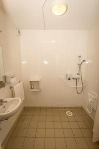 a white bathroom with a shower and a sink at So'Lodge Niort A83 in La Creche