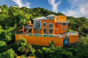 Vieques Villa Gallega - Oceanview w/Infinity Pool في بييكيس: منزل برتقالي مع مسبح في الاشجار