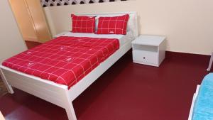 a white bed with red pillows and a red blanket at Casa de Férias in Tarrafal