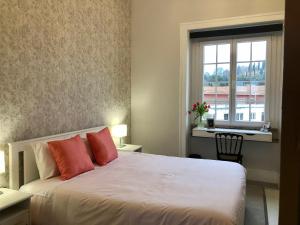 a bedroom with a bed with red pillows and a window at Thomar House in Tomar