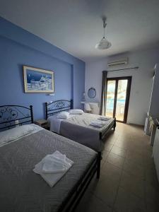 two beds in a room with blue walls at Stella Nomikou Apartments in Firostefani