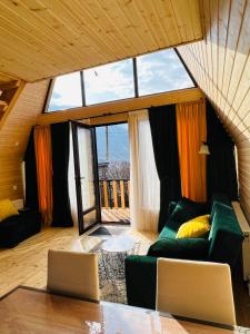 ein Wohnzimmer mit einem grünen Sofa und einem großen Fenster in der Unterkunft Emotion Kazbegi in Kazbegi