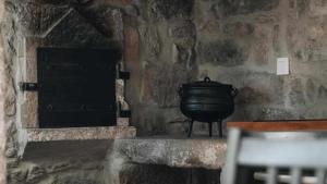 a stone fireplace with a large pot in a room at Casas do Vale A Casa Casa familiar in Nordeste