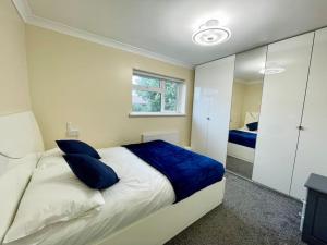 - une chambre avec un grand lit et des oreillers bleus dans l'établissement Luxurious Kitchen, 4BR Home with Free Parking near Airport for Contractor Holiday for 8 People, à Luton