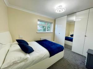 a bedroom with a large bed with blue pillows at Luxurious Kitchen, 4BR Home with Free Parking near Airport for Contractor Holiday for 8 People in Luton