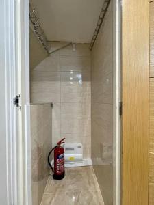 a bathroom with a fire extinguisher sitting on the floor at Luxurious Kitchen, 4BR Home with Free Parking near Airport for Contractor Holiday for 8 People in Luton