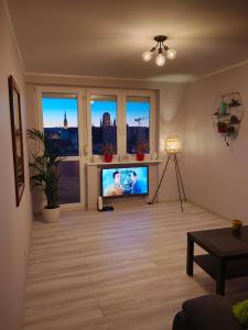 a living room with a flat screen tv and two windows at Apartament Długie Ogrody 2 pokojowy in Gdańsk