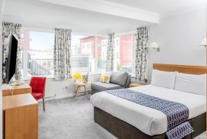 um quarto de hotel com uma cama e uma cadeira em The Kilbirnie Hotel em Newquay