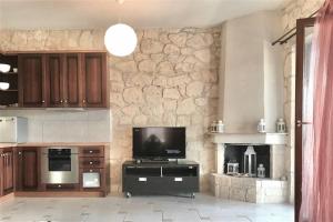 cocina con TV y pared de piedra en Ntinos House Elani Halkidiki, en Siviri