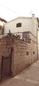 a building behind a brick wall with a fence at Nona Ružica in Vis