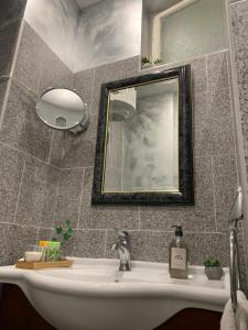 Dimora Apartman في ديبريتْسين: حمام مع حوض أبيض ومرآة