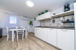 a kitchen with white cabinets and a table and chairs at Krcina Holiday Home in Cres