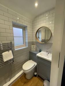 een badkamer met een toilet, een wastafel en een spiegel bij Haven Cottage, Cromer in Cromer