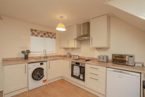 uma cozinha com armários brancos e uma máquina de lavar e secar roupa em Modern Cotswold Home em Witney
