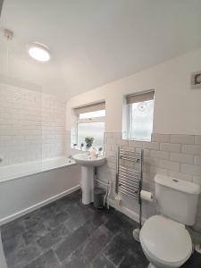 La salle de bains est pourvue de toilettes, d'un lavabo et d'une baignoire. dans l'établissement New Marston Apartment, à Oxford