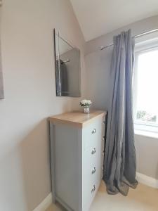 a room with a dresser with a mirror and a window at New Marston Apartment in Oxford