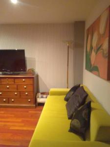 a living room with a yellow couch and a dresser at A Bruxo Fonte.8 pzs,2 bañs .Full in Luarca