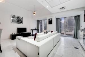 sala de estar blanca con sofá blanco y TV en Cayan Tower, Dubai Marina - Charming One Bedroom, en Dubái