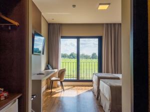 um quarto de hotel com uma cama, uma secretária e uma janela em Royal Tulip Holambra em Holambra