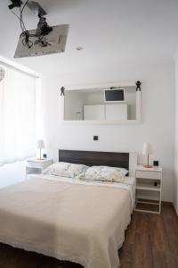 een witte slaapkamer met een groot bed en een spiegel bij Rovigno tesoro 1 in Rovinj