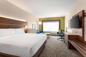Holiday Inn Express & Suites Austin North - Pflugerville, an IHG Hotel في بفلوغرفيل: غرفة فندقية بسرير كبير وتلفزيون بشاشة مسطحة
