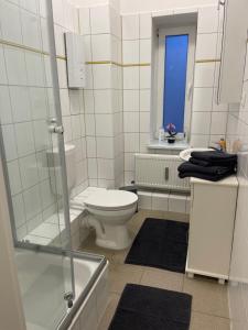 een witte badkamer met een toilet en een raam bij Schöne Wohnung am Schlossgarten in Schwerin