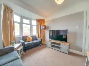 uma sala de estar com um sofá e uma televisão de ecrã plano em Rose Hill Apartment em Oxford