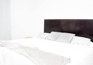 Una cama con sábanas blancas y almohadas. en Habitación Deluxe Aire - Villa Valle Campo 