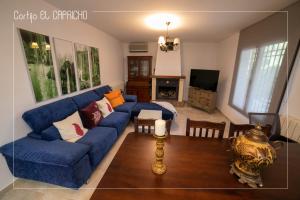 a living room with a blue couch and a tv at Cortijo El Segador y El Capricho in Almedinilla