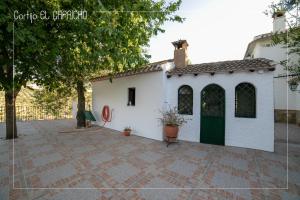 a white building with a green door on a patio at Cortijo El Segador y El Capricho in Almedinilla